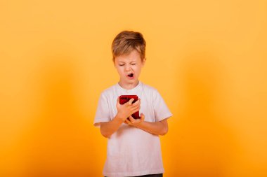 Stüdyoda sarı arka planda cep telefonuyla konuşan mutlu çocuk.