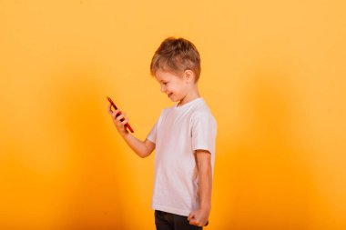 Stüdyoda sarı arka planda cep telefonuyla konuşan mutlu çocuk.