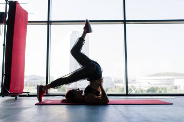 Spor salonunda halterli genç ve güzel bir bayan antrenman yapıyor. Eğitim için elementlerle poz vermek