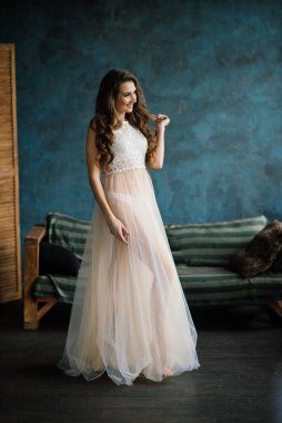 Beyaz iç çamaşırlı güzel gelin yatak odasında ve stüdyosunda oturuyor. Düğün konseptinin sabahı