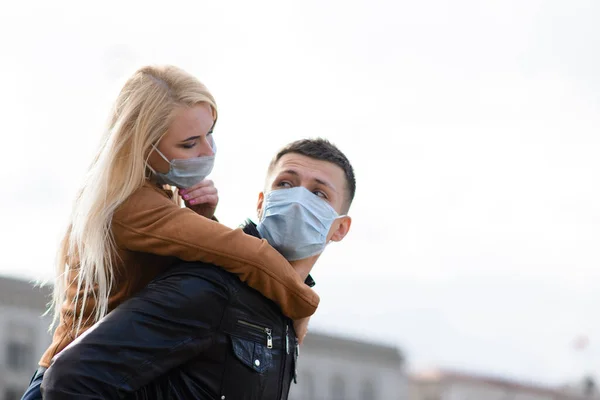 Young couple hugging wearing a face protection mask in the city center since new coronavirus have emerged.
