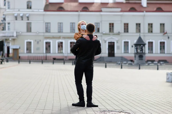 Young couple hugging wearing a face protection mask in the city center since new coronavirus have emerged.