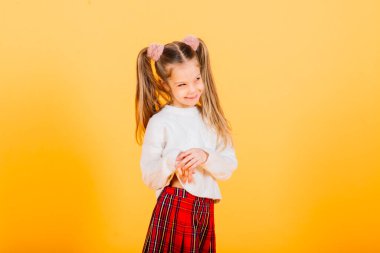 Gri arka planda kameraya bakan mutlu, küçük, güzel bir kız çocuğu. İnsan duyguları ve yüz ifadesi