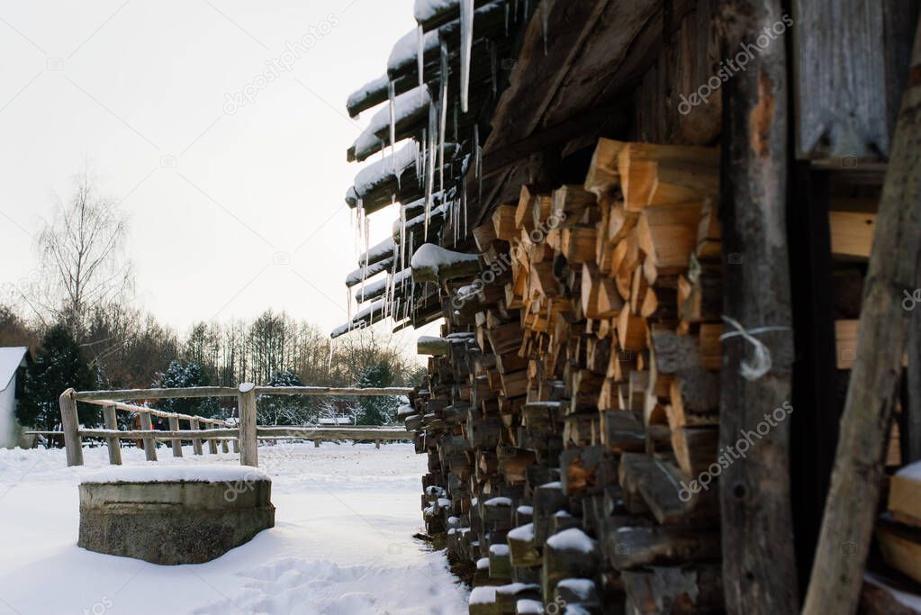 Woodpile of firewood on the outskirts of a farm, yard and winter forest