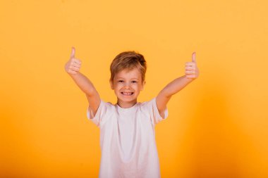 Stüdyoda sarı arka planda mutlu küçük bir çocuğun portresi