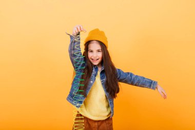 Gökkuşağı sinekliğiyle oynayan güzel bir genç kız. Stüdyo arka planında çocukluk oyuncağı.