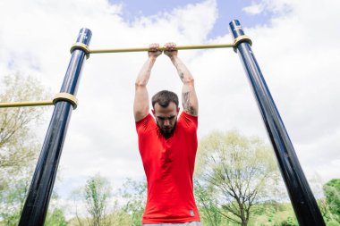 Beyaz tenli sporcu, sokak antrenmanı sırasında çapraz direkte elini kaldırıyor. Sağlıklı yaşam tarzı ve sokak sporu konsepti