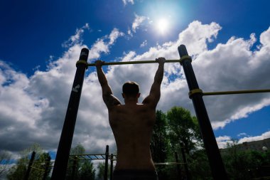 Beyaz tenli sporcu, sokak antrenmanı sırasında çapraz direkte elini kaldırıyor. Sağlıklı yaşam tarzı ve sokak sporu konsepti