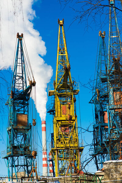 High factory structure and tower crane at industrial production area, blue sky