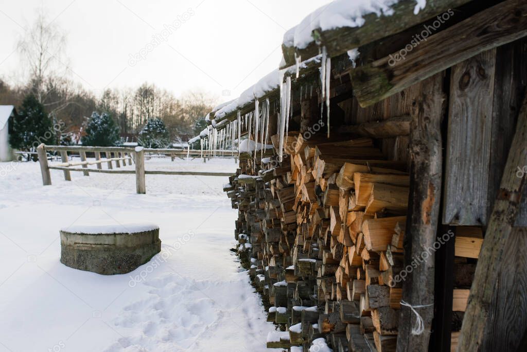 Woodpile of firewood on the outskirts of a farm, yard and winter forest