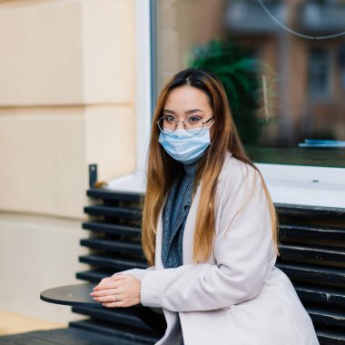 Grip virüsü grip virüslerine ve hastalıklara karşı koruyucu maske yayıyor. Halka açık yerlerde cerrahi maske takan Asyalı bir kadın. Sağlık Hizmetleri.