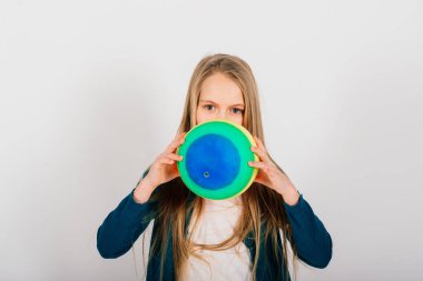 Güzel kız elinde renkli parlak bir top tutuyor, beyaz stüdyoda izole edilmiş.