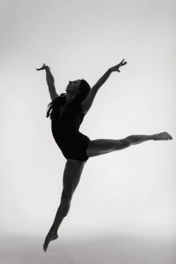 Bir kadın portresi, gri arka planda siyah bir elbise içinde dans eden bir balerin.