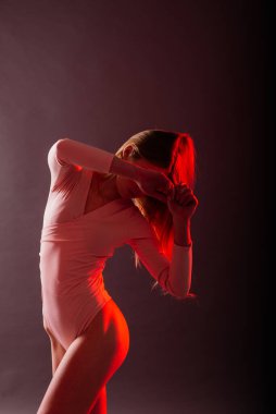 Renkli arka planda ince bir kadın, neon rengi bir elbise içinde poz veriyor.