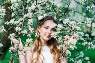 Beyaz gelinlikli gelin yeşil parkta bir buket tutuyor. Güneşli bir günde yaz düğünü..