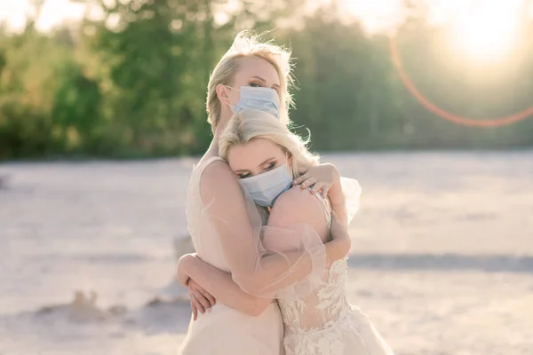 Lesbian couple wedding, wear masks to prevent epidemic covid, on sand background