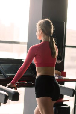 Alıştırma sırasında ve sonra spor salonunda koşu bandında koşan çekici sarışın beyaz kadın.