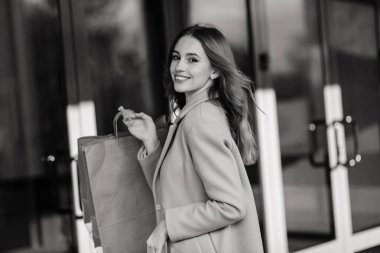 Dışarıdaki alışveriş torbalarını tutan neşeli genç bayan portresi.