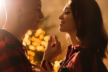 Genç ve çekici bir çift Noel ağacının yanında, erkek sevgiliye sürpriz yapar, nişan yüzüğü.