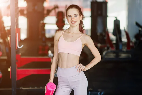 Young female at the gym trainer holding bottle of water