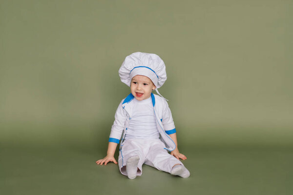 Portrait of a little boy cook holding pan at the kitchen. Different occupations. Isolated over white background. Twin brothers