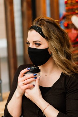 Kafkas görünümlü, siyah maskeli tatlı bir kadın, bir internet kafede oturuyor ve çalışıyor..