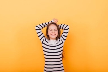 Güzel ve kendine güvenen bir kızın portresi sarı stüdyoda izole edilmiş duygularını gösteriyor.