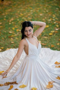 Güz parkında beyaz elbiseli güzel esmer bir kadın.