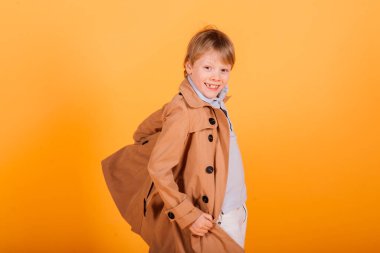 Sarı bir stüdyoda poz veren asık suratlı, duygusal, kızıl saçlı çocuk.