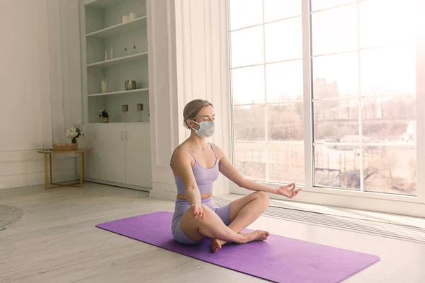 Young woman in a protective mask doing yoga, stay isolation at home for self quarantine.