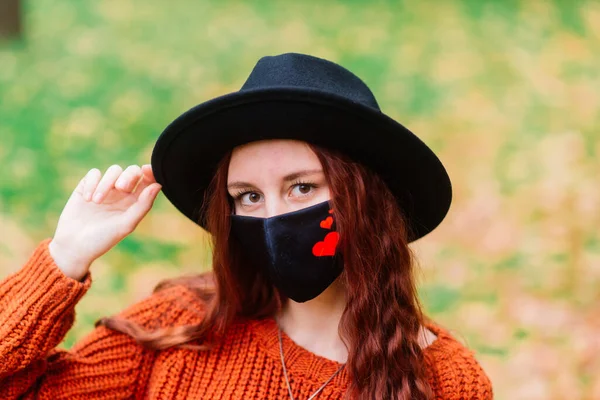 秋天的黄色公园里 身穿针织红毛衣 头戴黑色时髦口罩的年轻女子的画像 — 图库照片