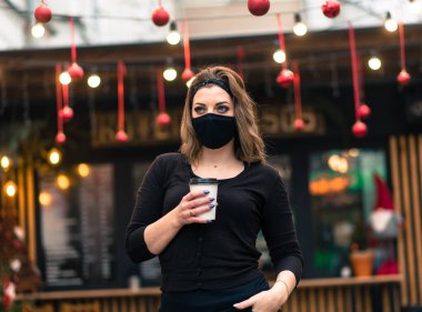 Kafkas görünümlü, siyah maskeli tatlı bir kadın, bir internet kafede oturuyor ve çalışıyor..