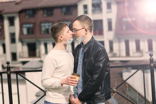若いですゲイカップル身に着けています医療マスク 抱擁とキスで街 — ストック写真