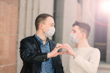 Tıbbi maske takan genç eşcinsel çift şehirde sarılıyor..