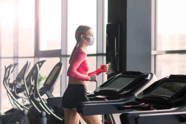Corona virüsü salgını sırasında spor salonunda maske takan kadın.
