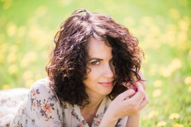 Bahar çiçekli bahçede poz veren kıvırcık saçlı çekici bir kadın.