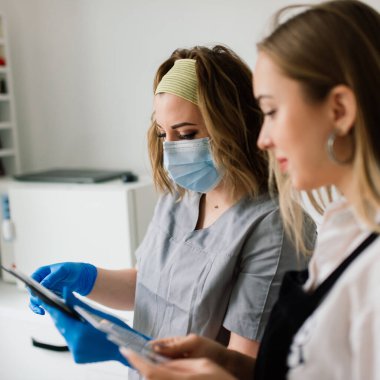 Güzellik salonunda kadın manikür ustası müşterinin elleriyle çalışıyor.