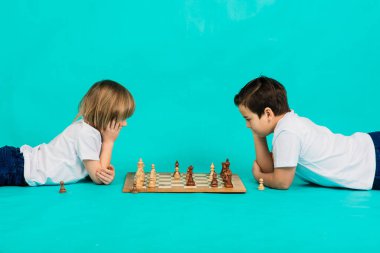 Stüdyoda satranç oynayan iki ciddi çocuk, mavi arka plan