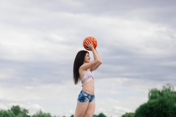身穿运动衫和运动裤的年轻女运动员在室外篮球场打球 — 图库照片