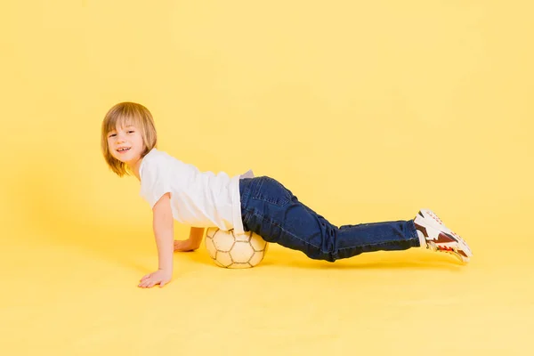 Cute Boy Trzyma Piłkę Nożną Prawdziwej Skóry Izolowane Żółtym Tle — Zdjęcie stockowe