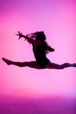 Duman içinde dans eden profesyonel balerin. Arka planda siyah elbiseli bir kadın..