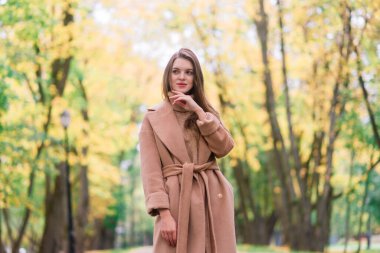 Sonbahar parkında yürüyen sarışın genç bayan..