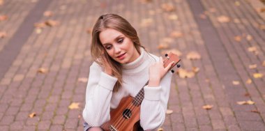 Güz ormanlarında gitar çalan güzel bir kadın.