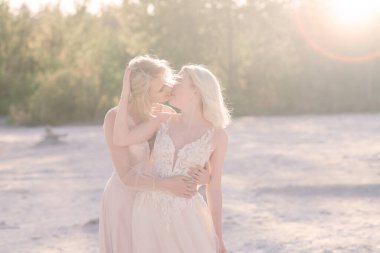 Güzel lezbiyen çift düğün günlerinde kumların üzerinde yürüyorlar.