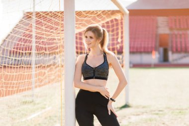 Spor giyim sektöründe genç ve güzel bir kız sporcu stadyumda antrenman yapıyor ve koşuyor.