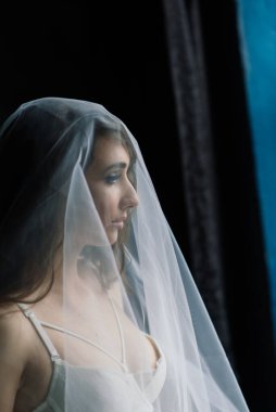 Beyaz iç çamaşırlı güzel gelin yatak odasında ve stüdyosunda oturuyor. Düğün konseptinin sabahı