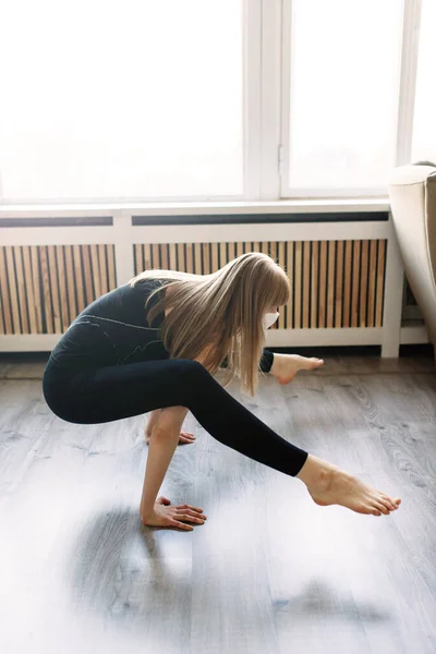 Meditating woman wearing a medical face mask to protect from corona virus covid-19, yoga position