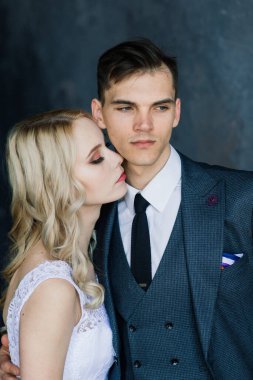 Klasik bir stüdyonun içinde şirin bir düğün çifti. Öpüşüyorlar ve sarılıyorlar..