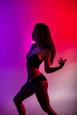 Gri arka planda izole edilmiş fitness baştan çıkarıcı kadın pozu.