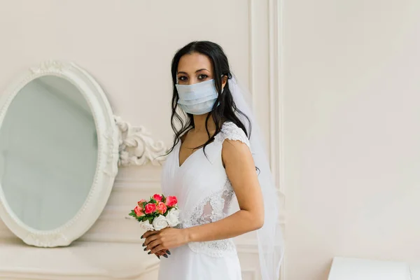 African American bride in dress, mask and in morning preparing for the wedding in hotel room